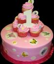 Butterfly Dots 1st Birthday Cake. Pink buttercream iced, round decorated with butterflies, circles and dots, topped with cupcakes. Everything on this cake is edible. (Serves 8-80 party slices.) 